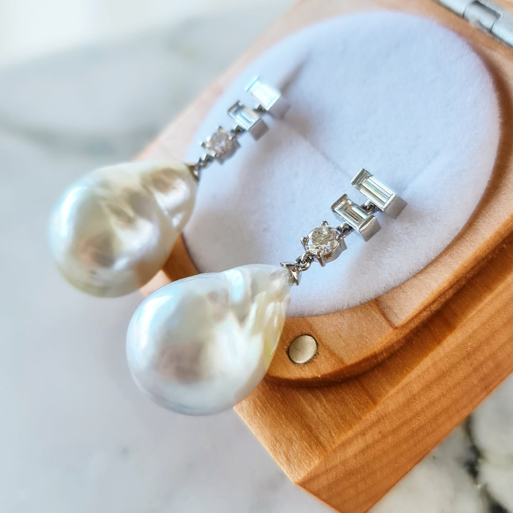A close-up of a Women's diamond earrings with Natural Baroque Pearl placed in a wooden box holder