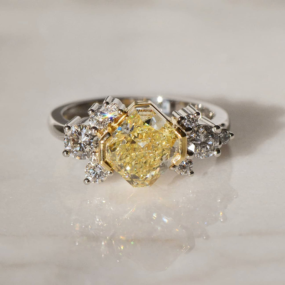 A close-up of Cushion Cut Yellow Diamond Ring placed atop a shiny surface