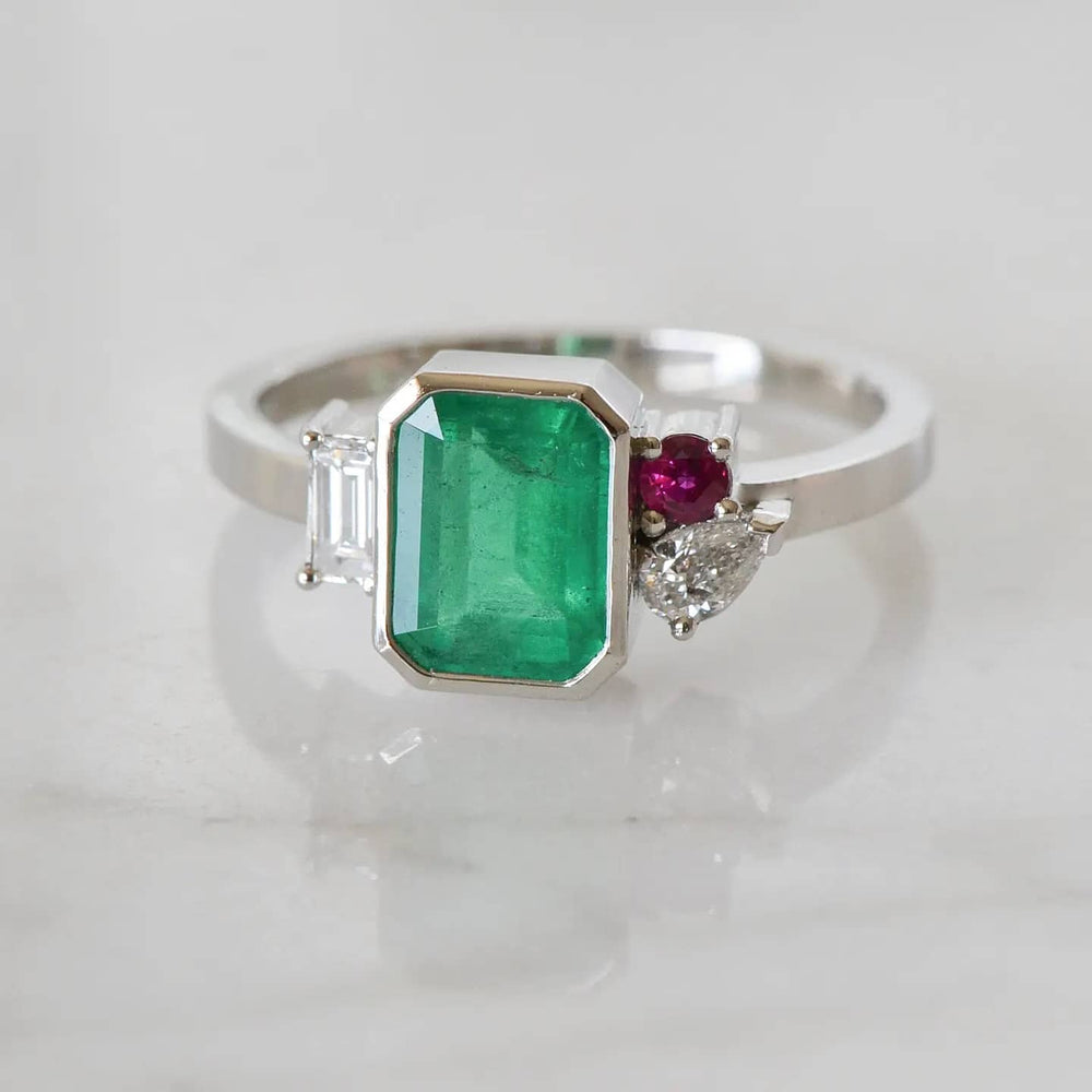 A close-up of a Light Green Emerald Cut Diamond Ring placed on top of a shiny white surface