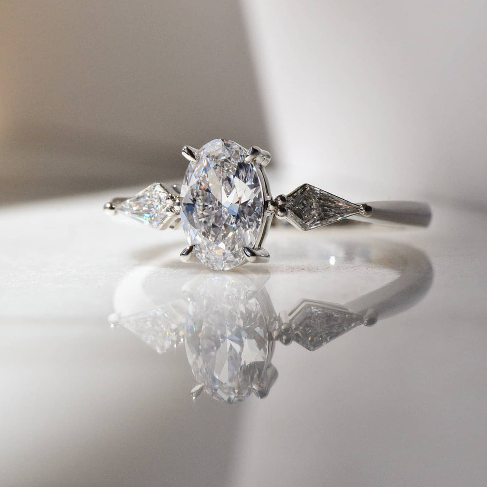 A stunning Oval Cut Diamond engagement ring with its reflection on a white shiny surface