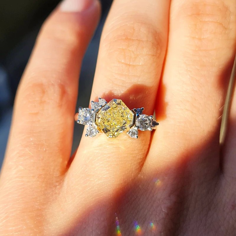 A close-up of a hand in bright sunlight with Radiant Cut Fancy Light Yellow Diamond Ring on its ring Finger