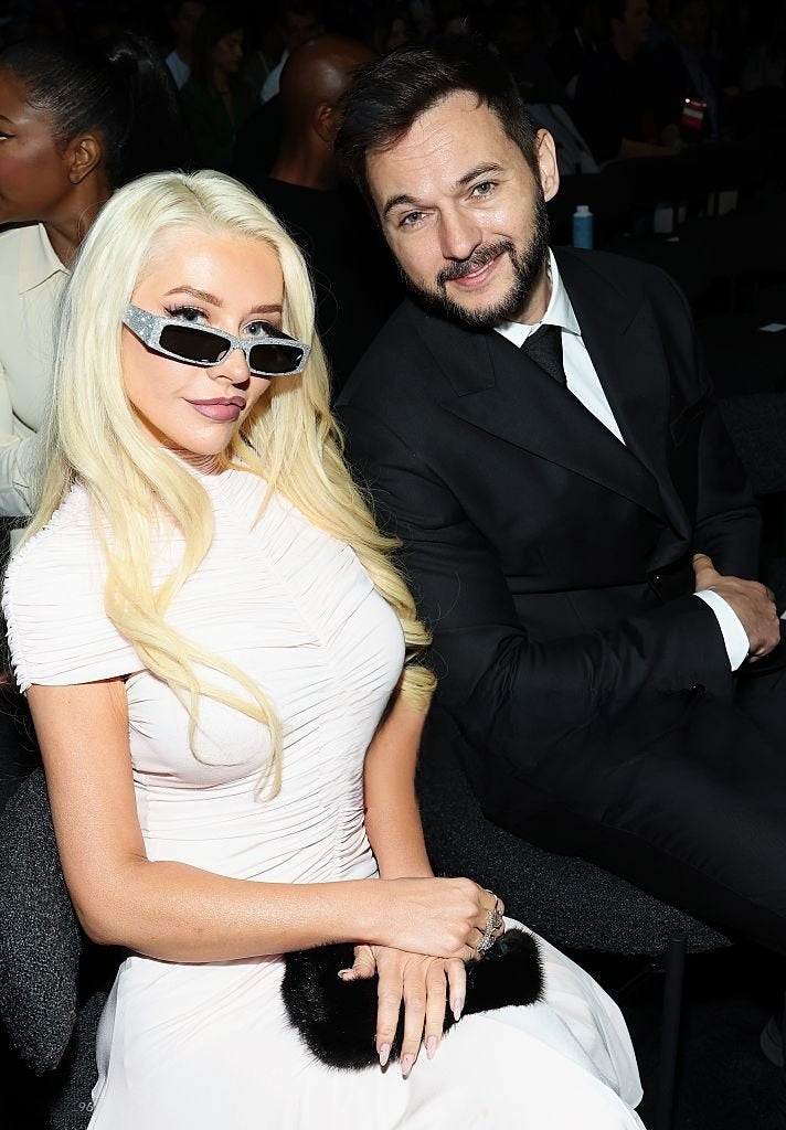 Christina Aguilera and her husband (Matthew Rutler) photographed in a white dress at the Air Bnb Summer Release Event. Aguilera wears LKC rings from the OUTRÉ Edit.