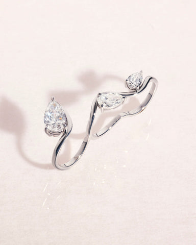 18ct white gold three-finger ring with pear cut diamonds on a light pink background