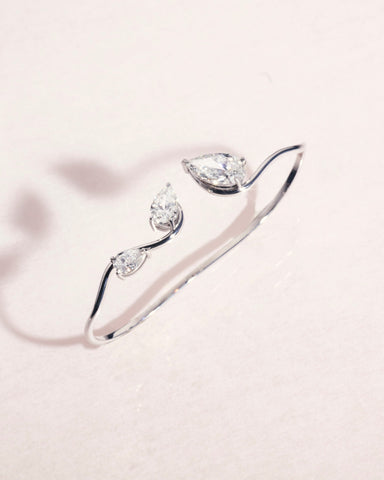 18ct white gold hand cut with three pear cut diamonds on a light pink background