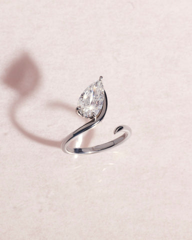 18ct white gold ring with a pear cut diamond on a light pink background