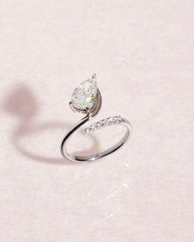 18ct white gold ring with a pear cut diamond on a light pink background