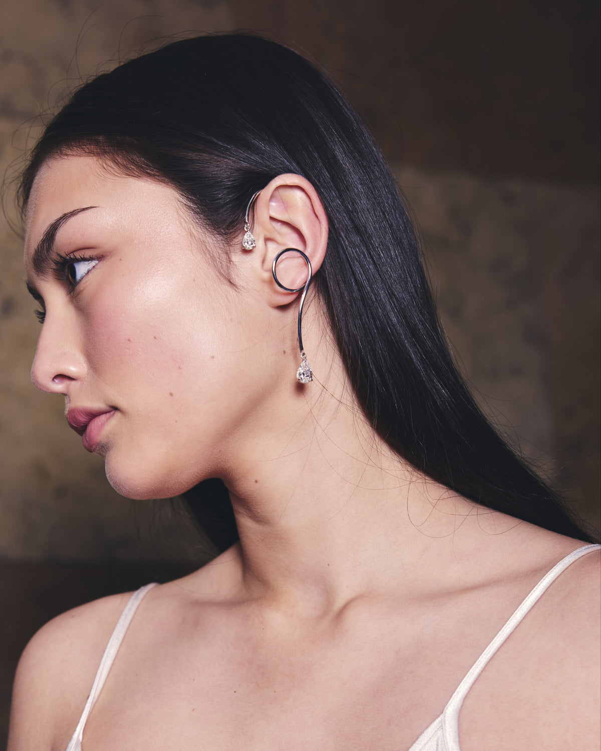 Woman wearing a white gold and diamond cuff earring in an elegant backdrop