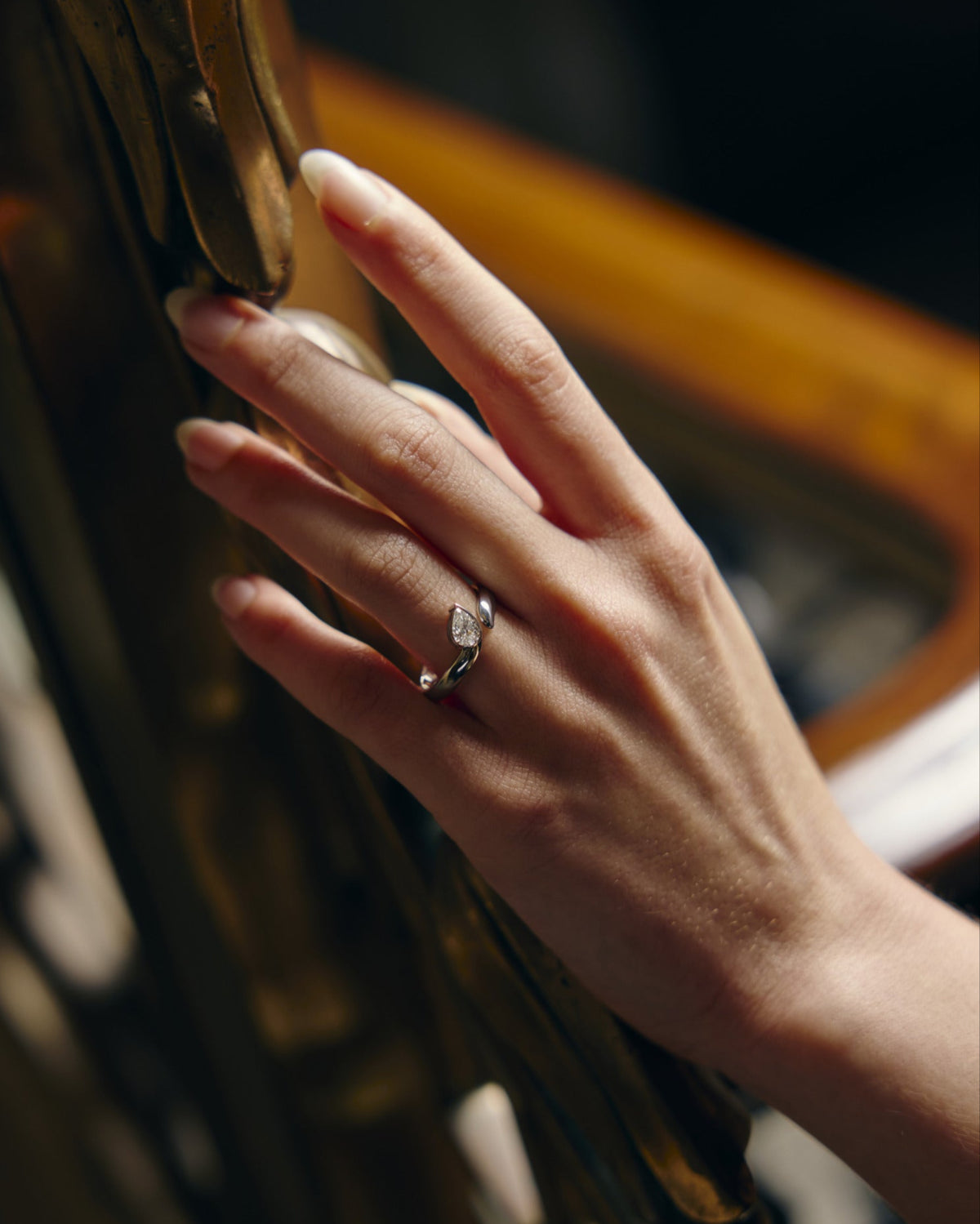 Hand with a white gold and diamond ring on a brass hand rail