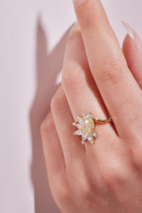 yellow diamond ring worn on the middle finger on a hand with a light background