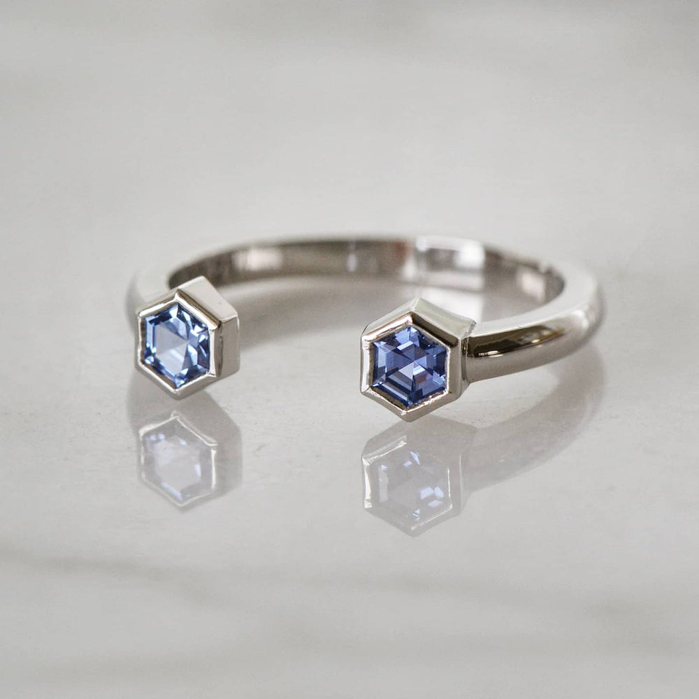 A close-up of a Hexagon Shaped Blue Engagement Ring placed atop a shiny white surface