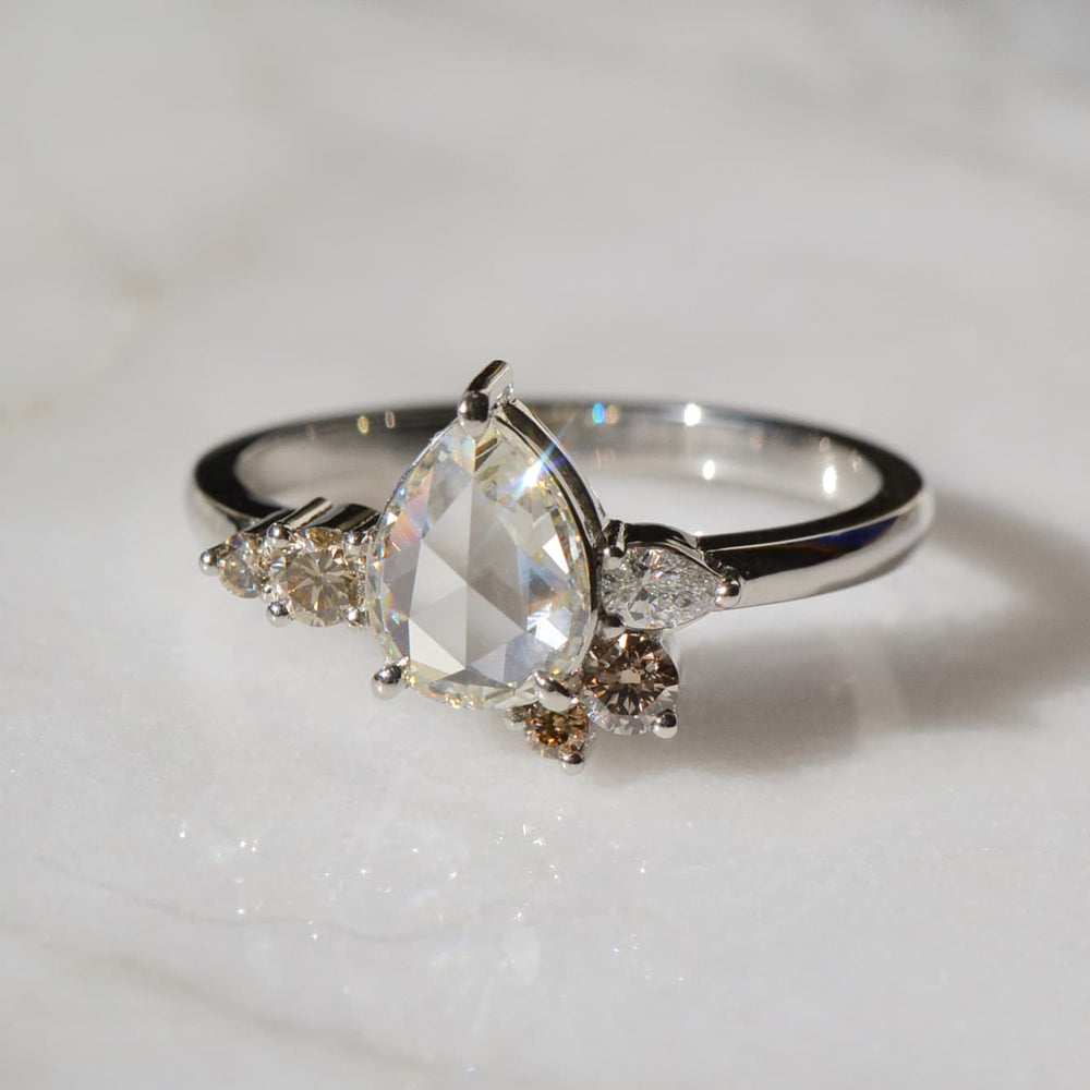 A close-up of a Pear shaped Diamond Ring placed on a white surface