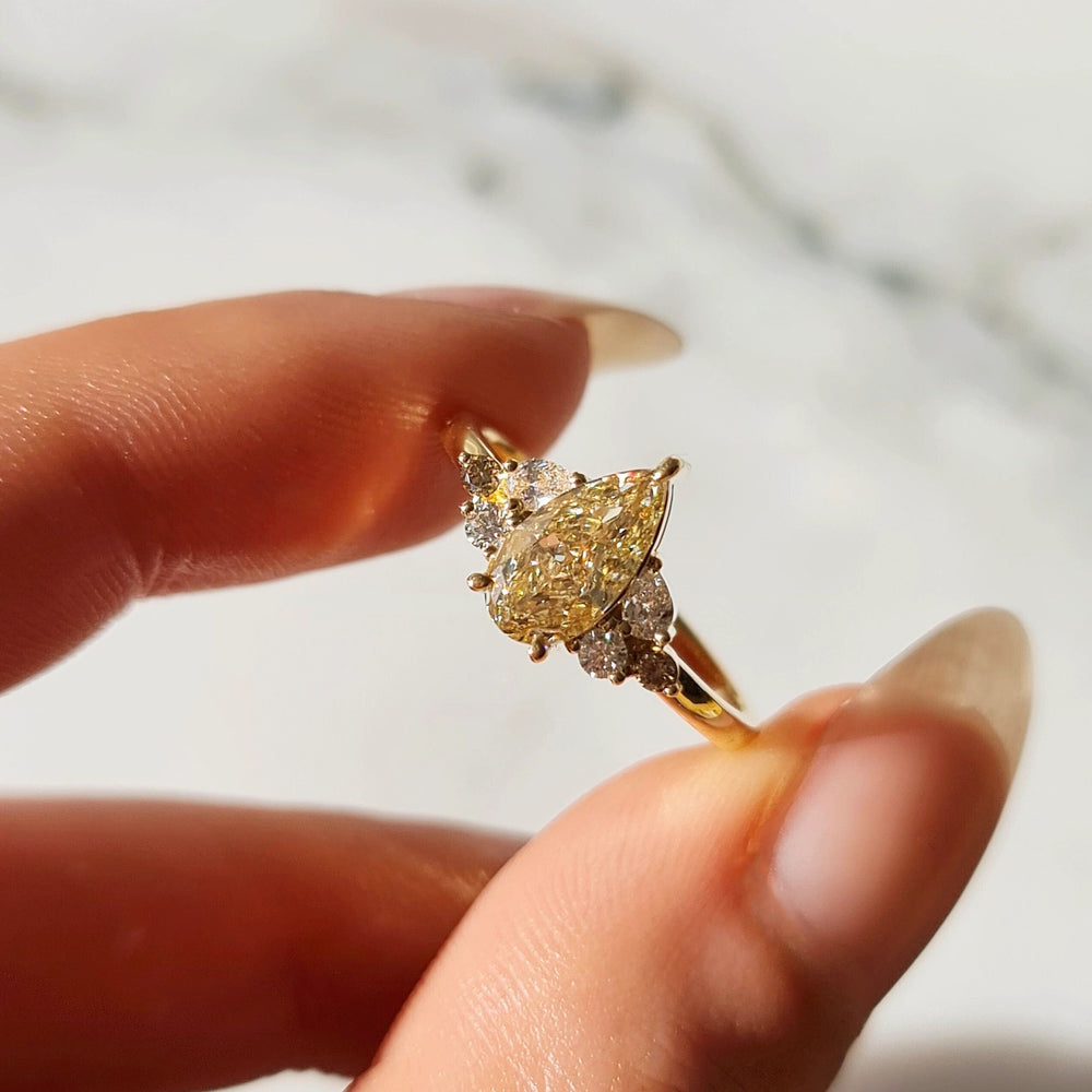 A close-up of two fingers holding an appealing Pear Cut Yellow Diamond Ring 