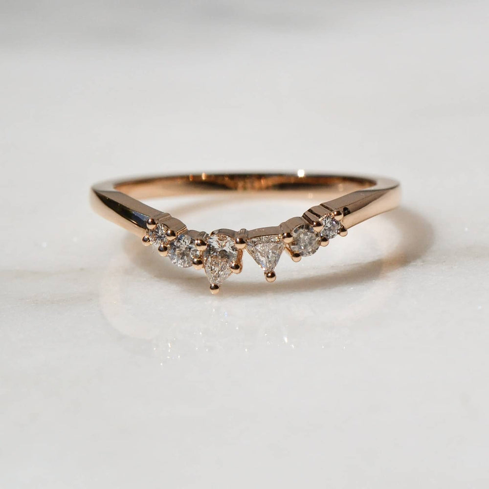 A close-up of a Pear cut Diamond Nesting Wedding Ring placed on white surface