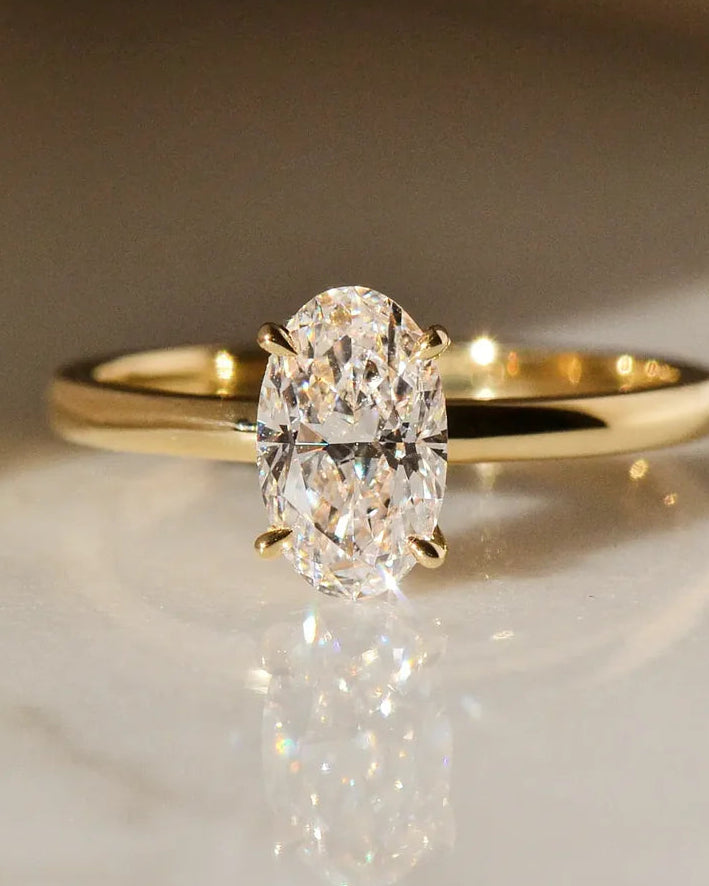 Gold ring with a diamond on a marble surface