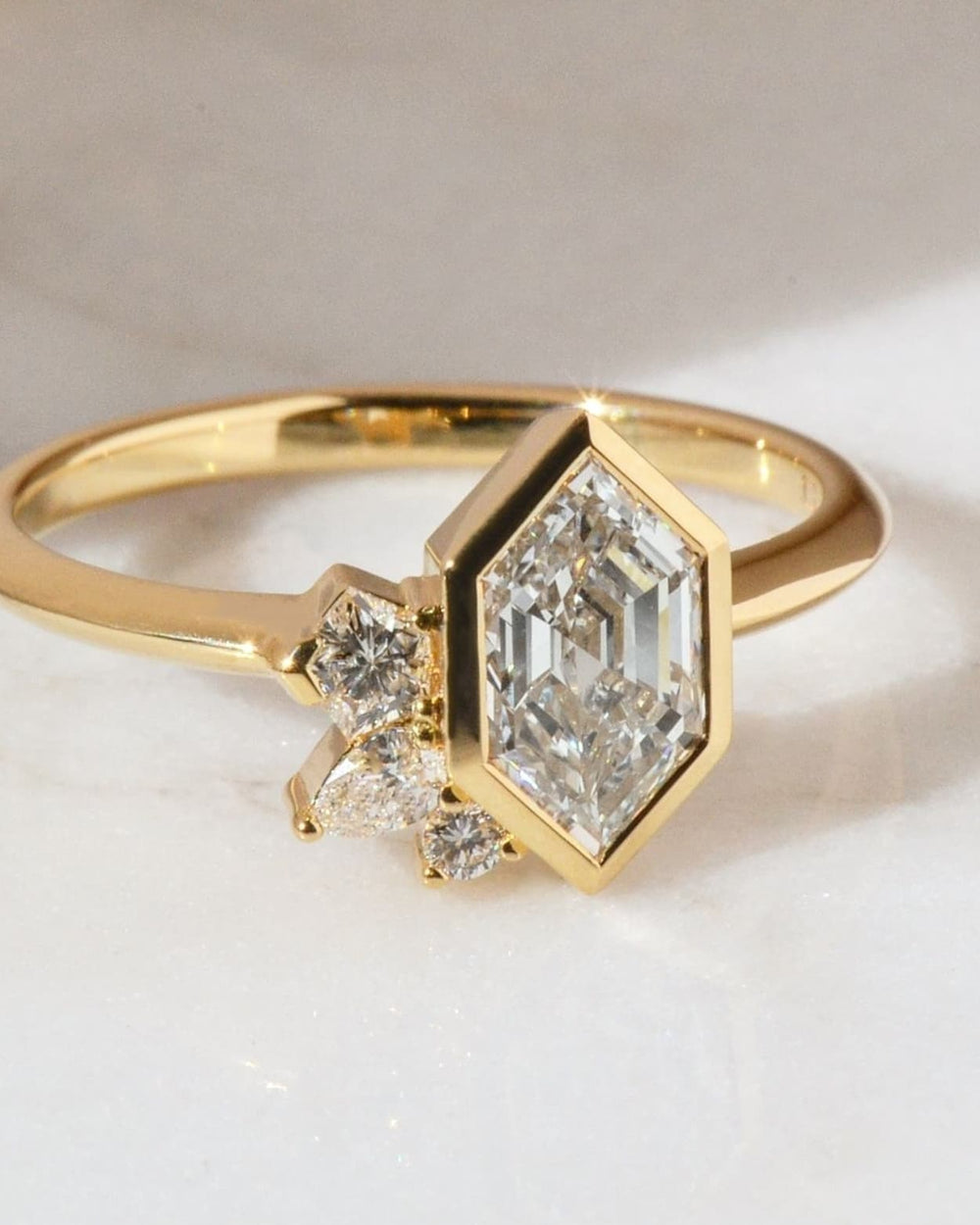 Gold ring with a hexagonal diamond on a light background