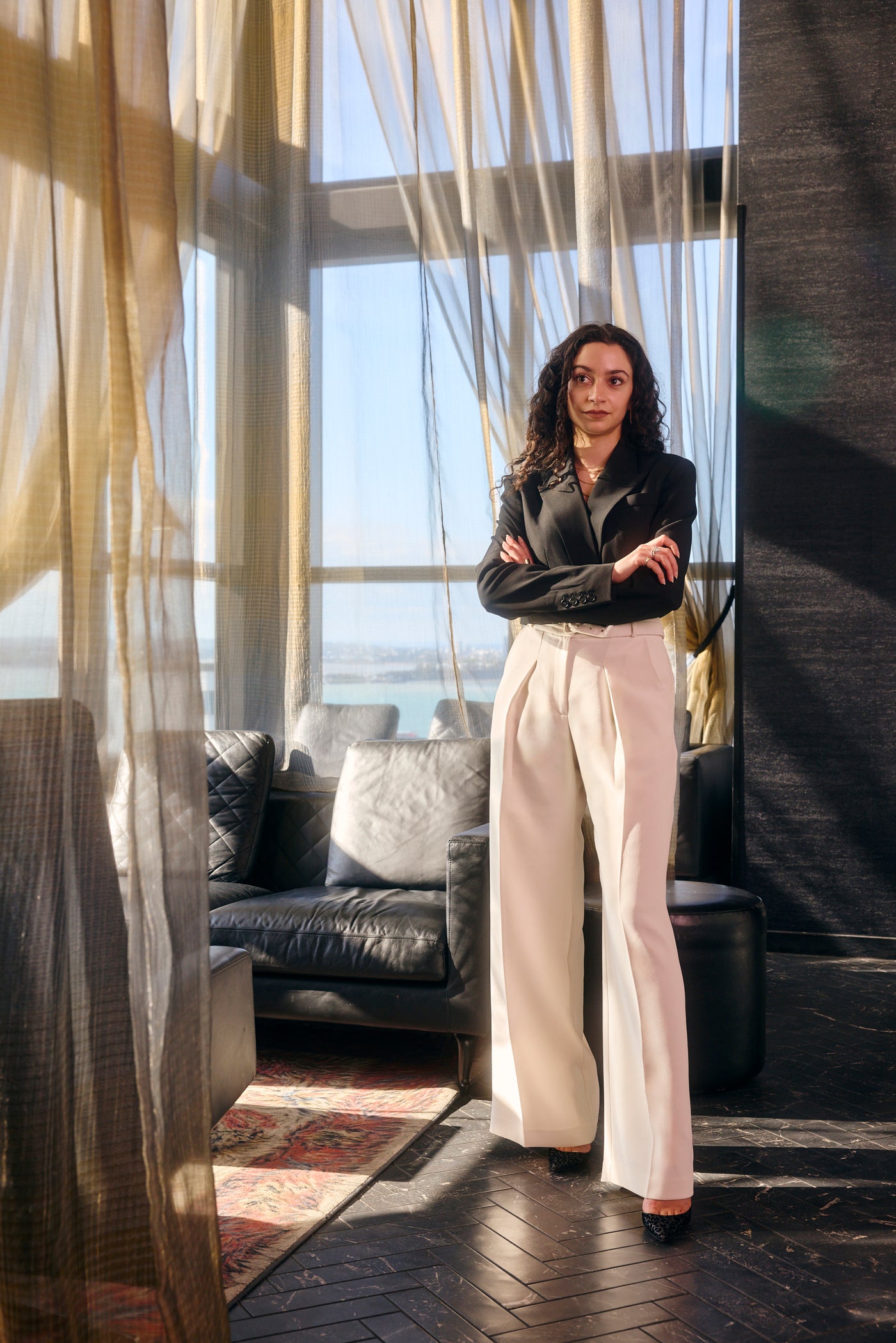 Woman standing in an elegant room with modern decor, black marble floor, and large windows.