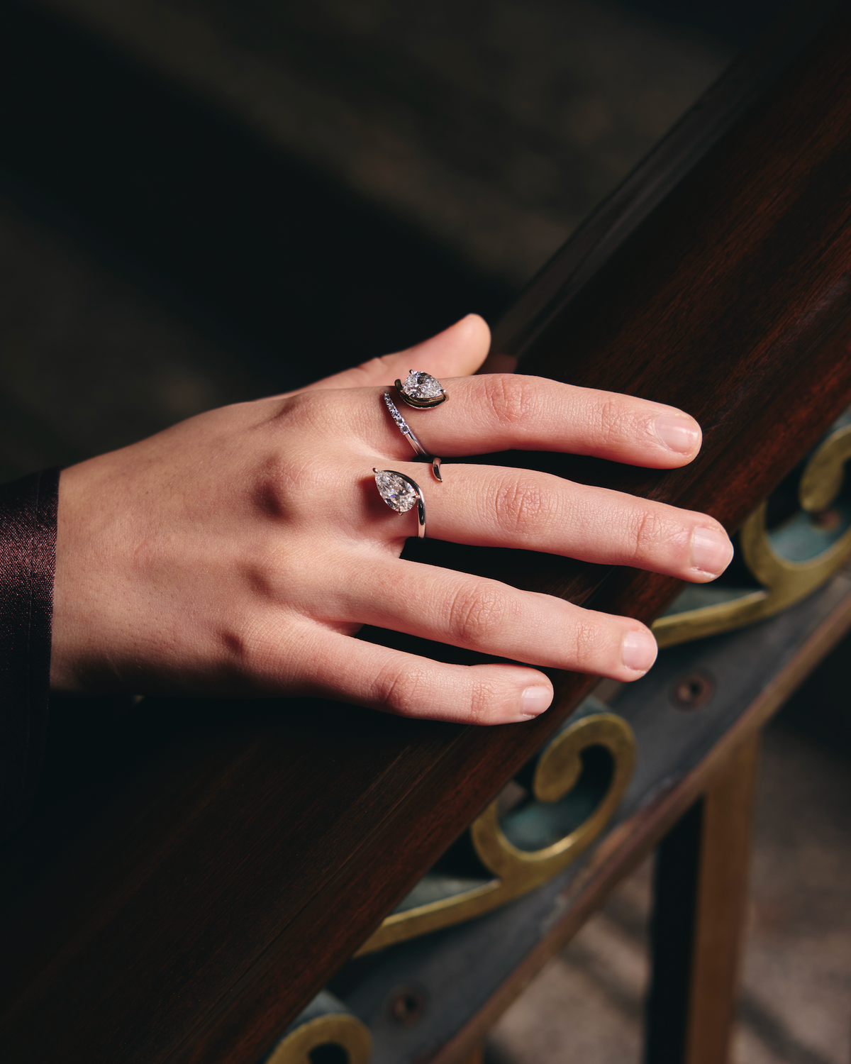 Hand with multiple rings on a wooden surface
