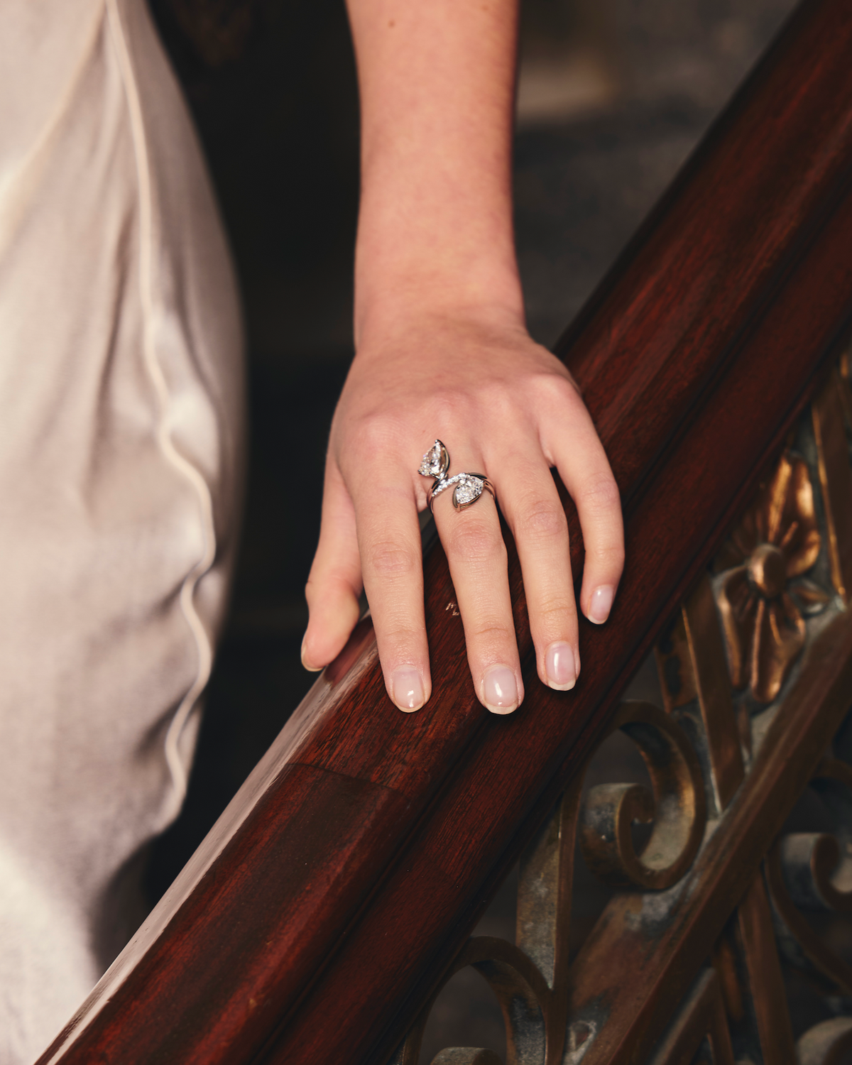 Hand with multiple diamond rings on a wooden handrail