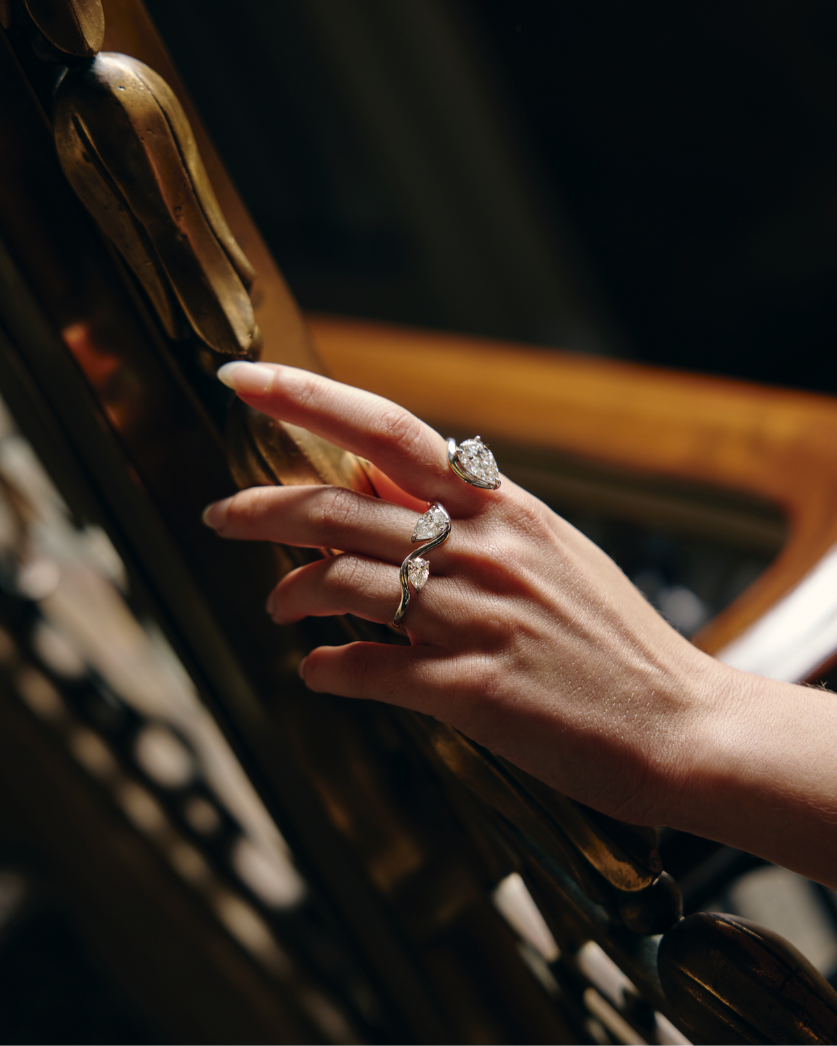 Hand with diamond rings on a brass wooden handrail