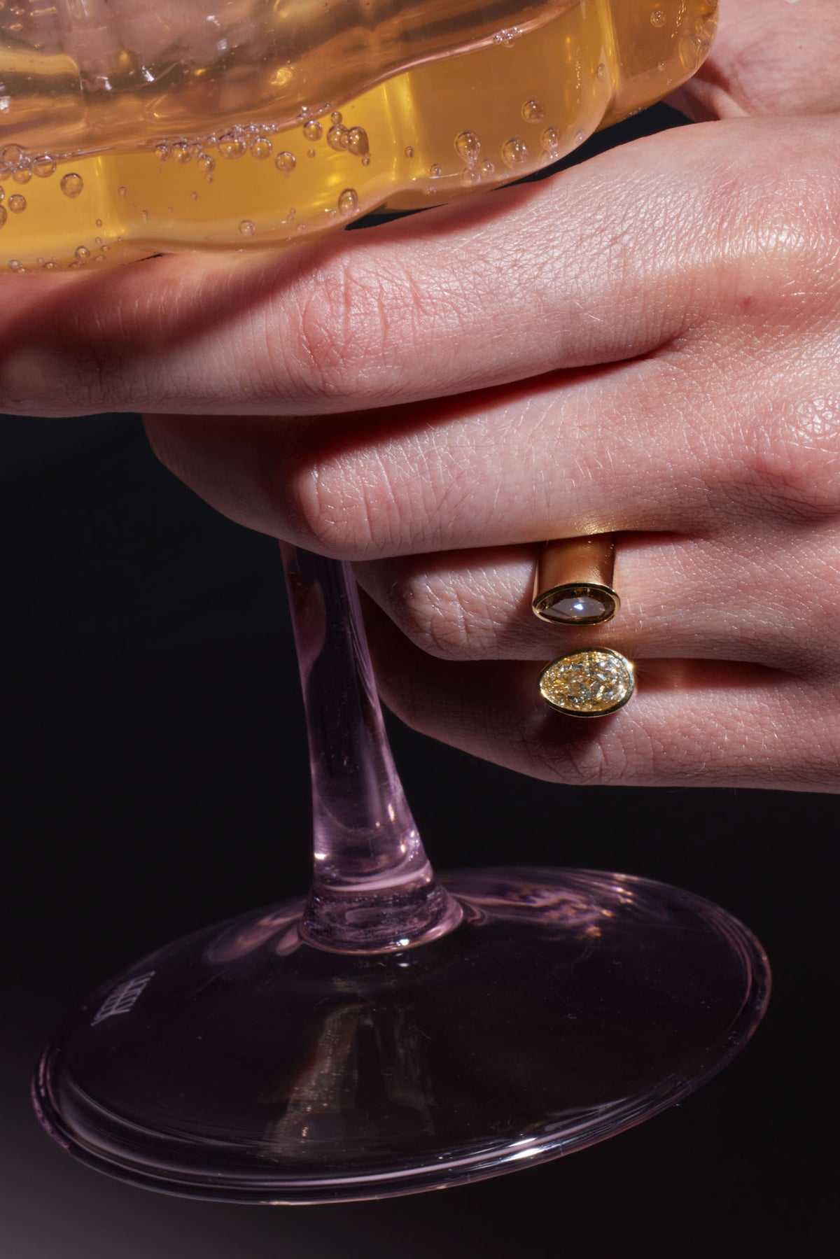 A close-up of a hand holding a glass wearing a Toi et Moi Diamond Ring.