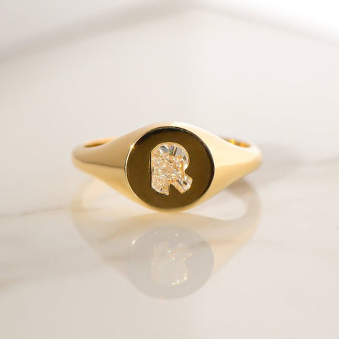 A beautiful 18ct Gold Signet Ring placed on a shiny surface.