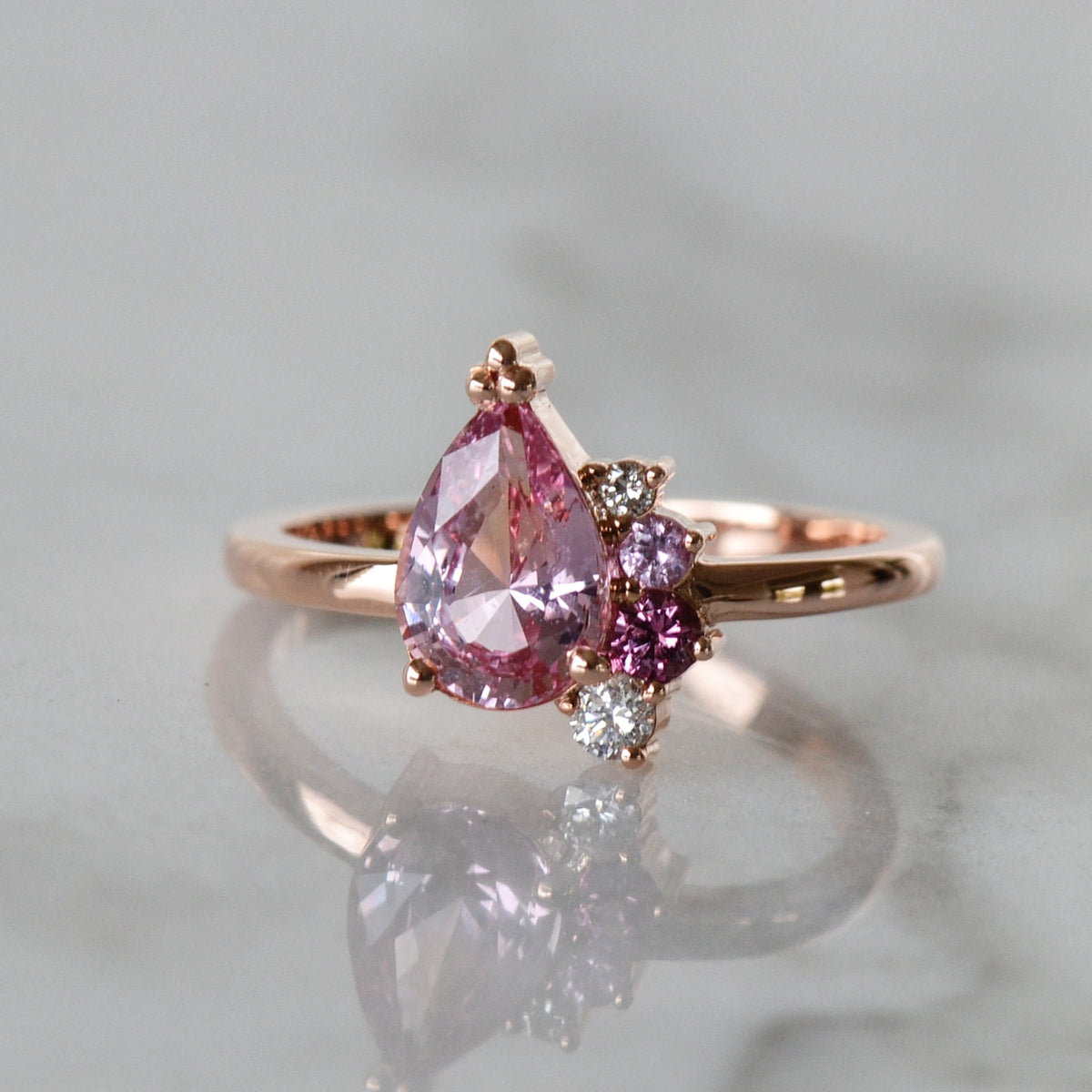 A stunning Rose Gold Pear Cut Engagement Ring placed on the shiny surface..